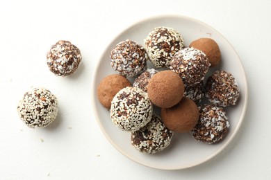 Photo of Tasty chocolate candies with cocoa powder, nuts and sesame seeds on white table, top view
