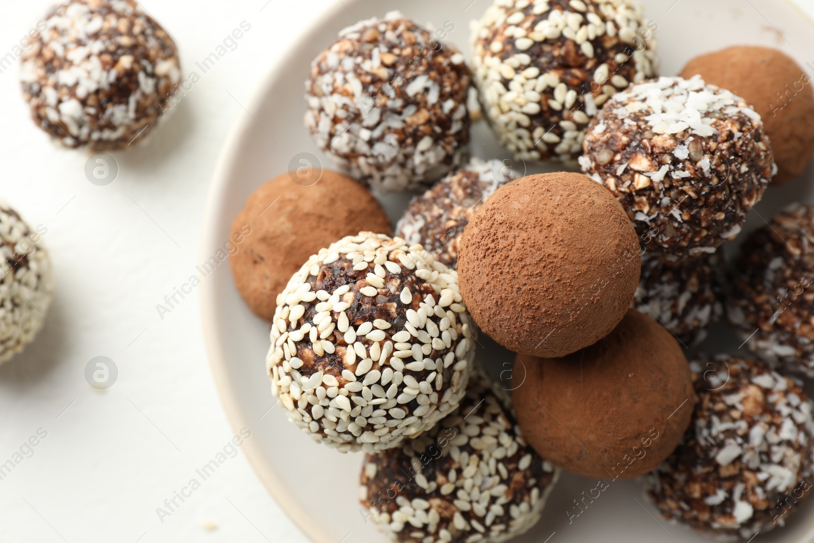 Tasty chocolate candies with cocoa powder, nuts and sesame seeds on white table, top view Photo of Tasty chocolate candies with cocoa powder, nuts and sesame seeds on white table, top view