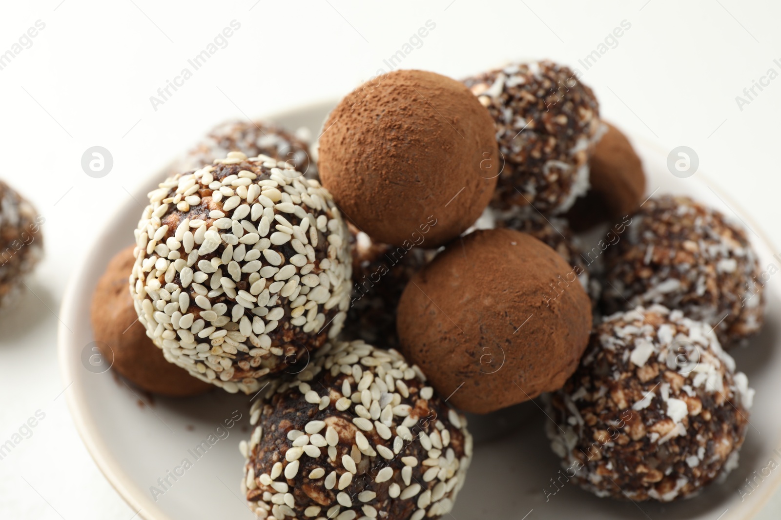 Tasty chocolate candies with cocoa powder, nuts and sesame seeds on table, closeup Photo of Tasty chocolate candies with cocoa powder, nuts and sesame seeds on table, closeup