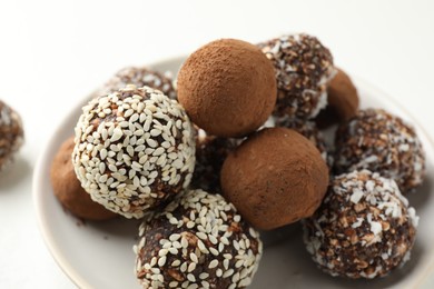 Photo of Tasty chocolate candies with cocoa powder, nuts and sesame seeds on table, closeup