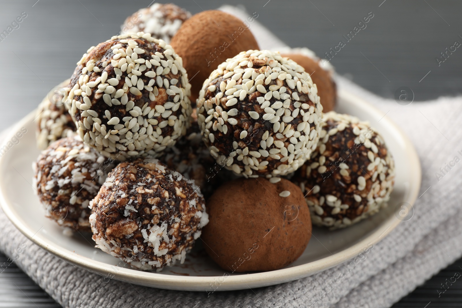 Tasty chocolate candies with cocoa powder, nuts and sesame seeds on table, closeup Photo of Tasty chocolate candies with cocoa powder, nuts and sesame seeds on table, closeup