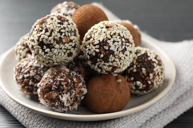 Photo of Tasty chocolate candies with cocoa powder, nuts and sesame seeds on table, closeup