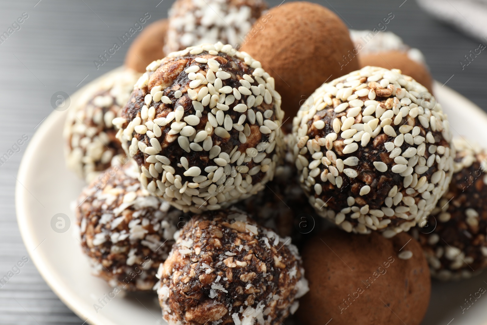 Tasty chocolate candies with cocoa powder, nuts and sesame seeds on table, closeup Photo of Tasty chocolate candies with cocoa powder, nuts and sesame seeds on table, closeup