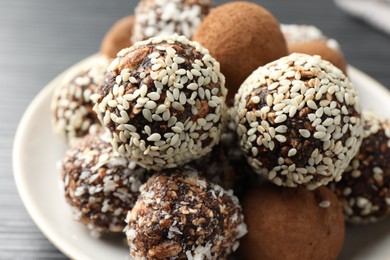 Photo of Tasty chocolate candies with cocoa powder, nuts and sesame seeds on table, closeup