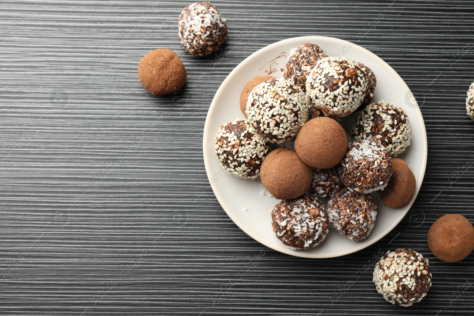 Tasty chocolate candies with cocoa powder, nuts and sesame seeds on black textured table, flat lay. Space for text Photo of Tasty chocolate candies with cocoa powder, nuts and sesame seeds on black textured table, flat lay. Space for text