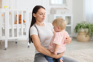 Photo of Mother with cute little baby on floor in room