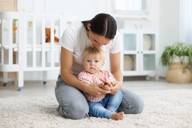 Photo of Mother with cute little baby on floor in room