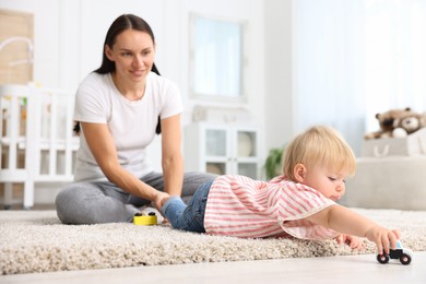 Photo of Mother with cute little baby on floor in room