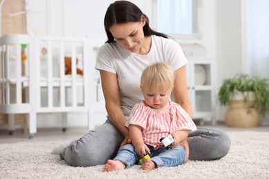 Photo of Mother with cute little baby on floor in room