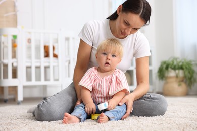 Photo of Mother with cute little baby on floor in room