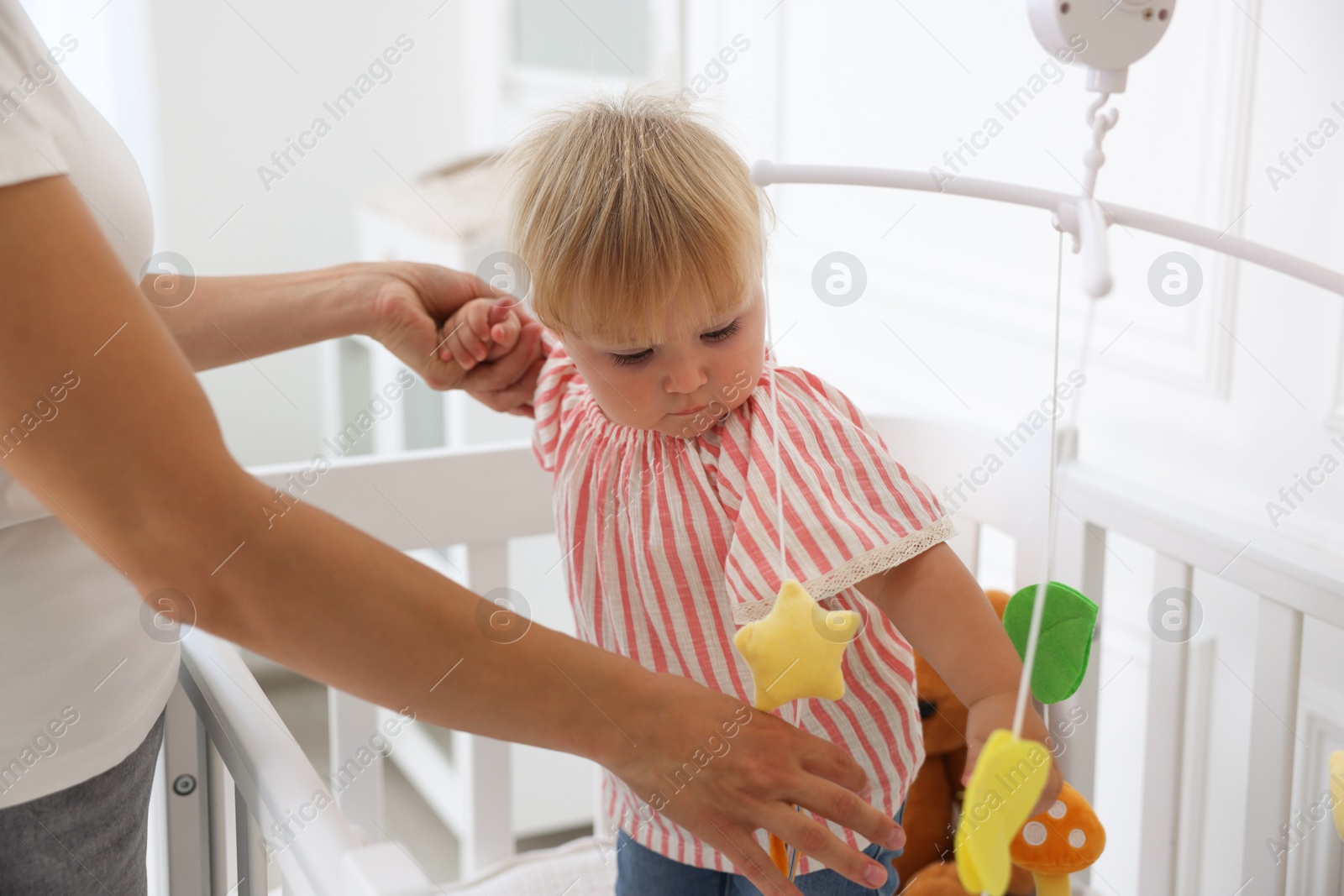 Mother with her cute little baby in crib in room, closeup Photo of Mother with her cute little baby in crib in room, closeup
