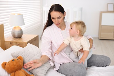 Photo of Mother with her cute little baby and toy on bed in room
