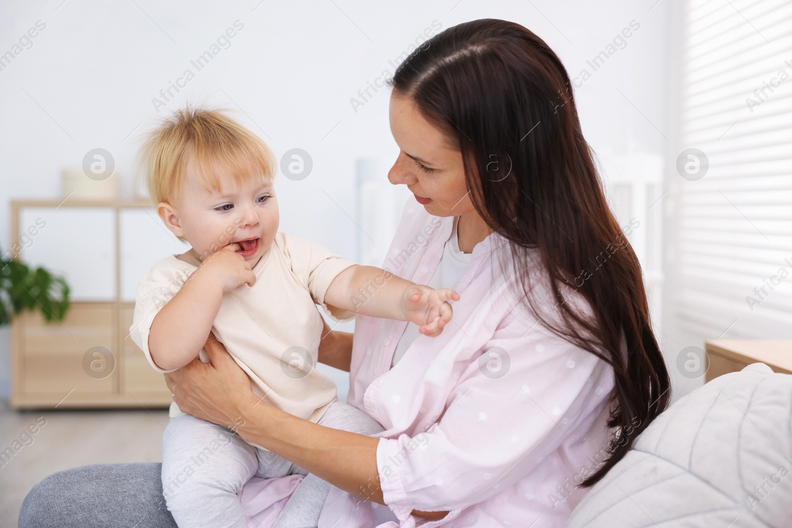 Mother with her cute little baby on bed in room Photo of Mother with her cute little baby on bed in room