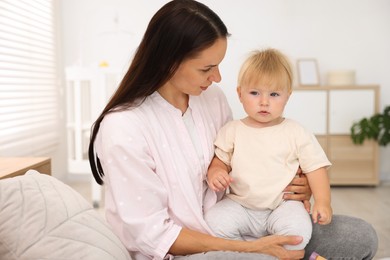 Photo of Mother with her cute little baby on bed in room