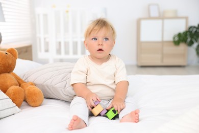 Photo of Cute little baby playing with toys on bed in room