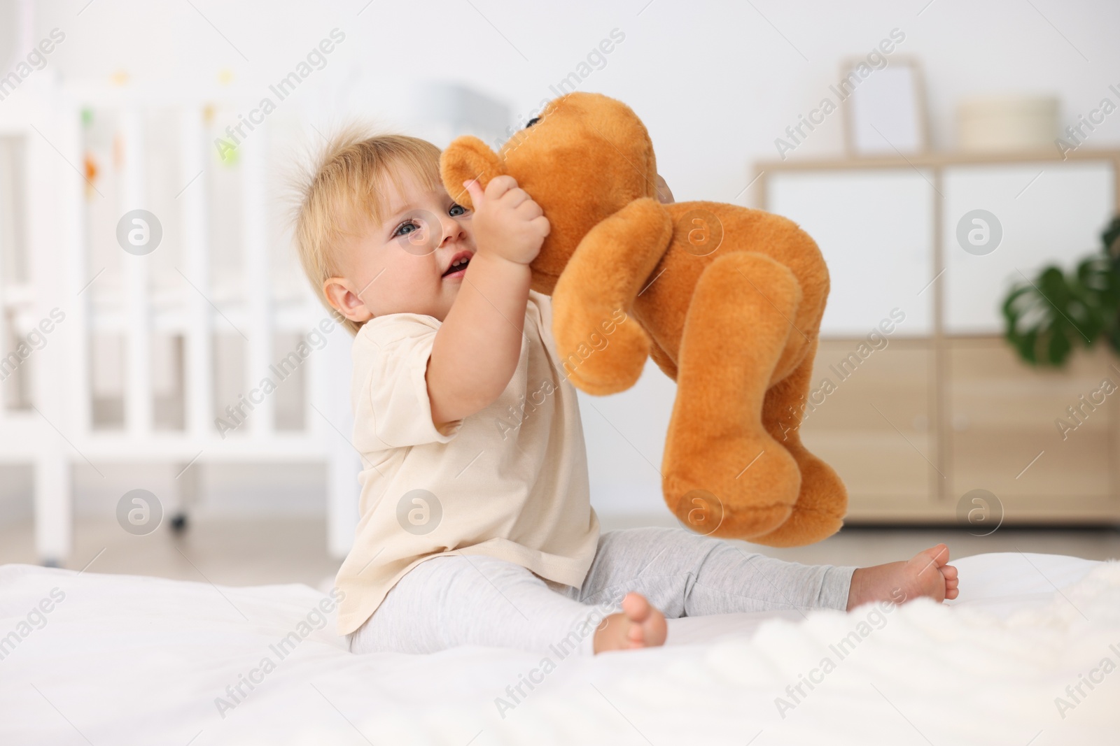 Cute little baby playing with toy on bed in room Photo of Cute little baby playing with toy on bed in room