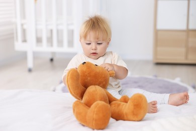 Photo of Cute little baby playing with toy on bed in room