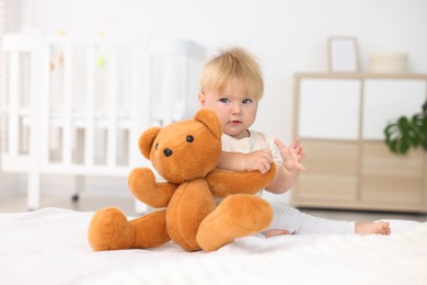 Photo of Cute little baby playing with toy on bed in room