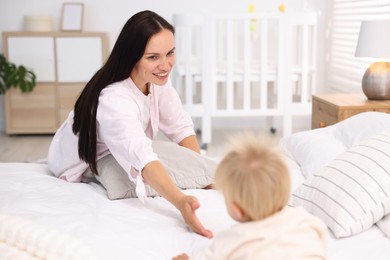 Photo of Mother and her cute little baby on bed in room