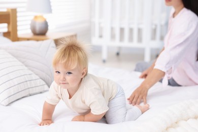 Photo of Mother and her cute little baby on bed in room, closeup
