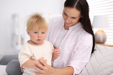 Photo of Mother and her cute little baby on bed in room