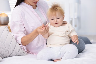 Photo of Mother and her cute little baby on bed in room, closeup
