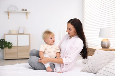 Photo of Mother and her cute little baby on bed in room