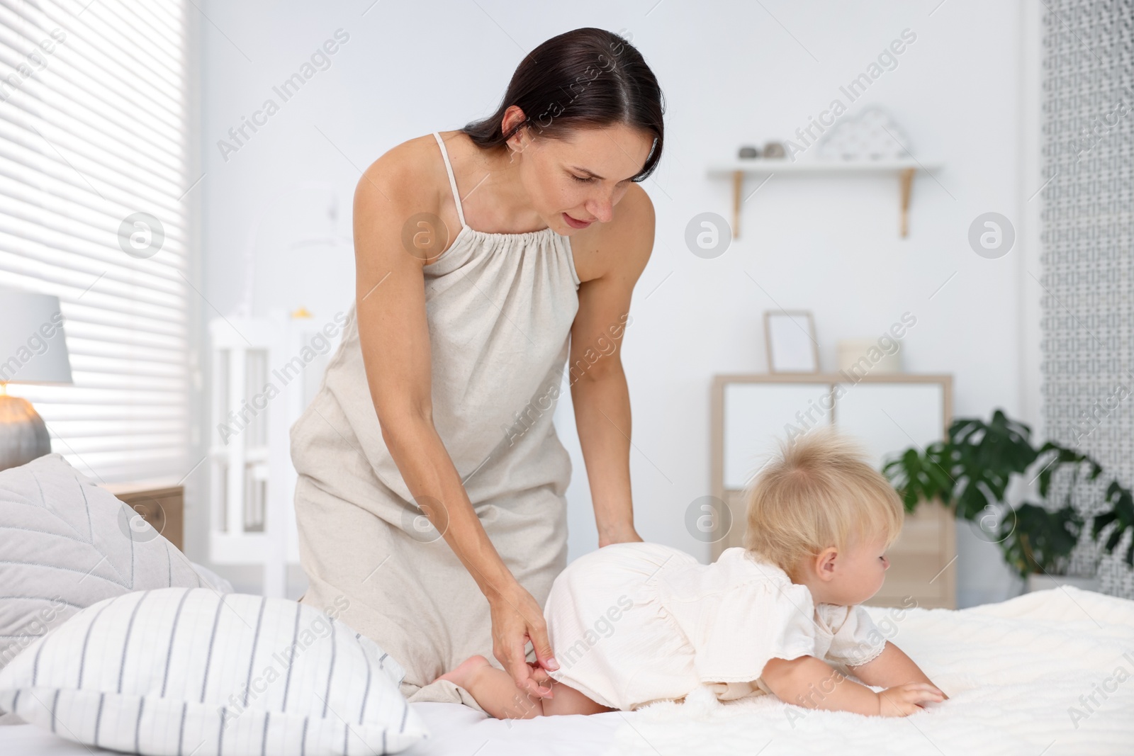 Mother and her cute little baby on bed in room Photo of Mother and her cute little baby on bed in room
