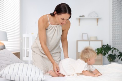 Photo of Mother and her cute little baby on bed in room