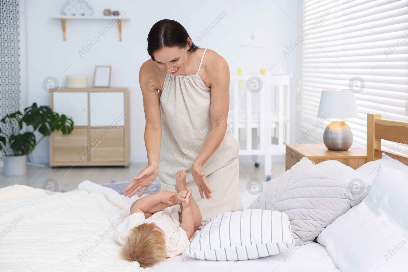 Mother and her cute little baby on bed in room Photo of Mother and her cute little baby on bed in room