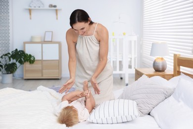 Photo of Mother and her cute little baby on bed in room