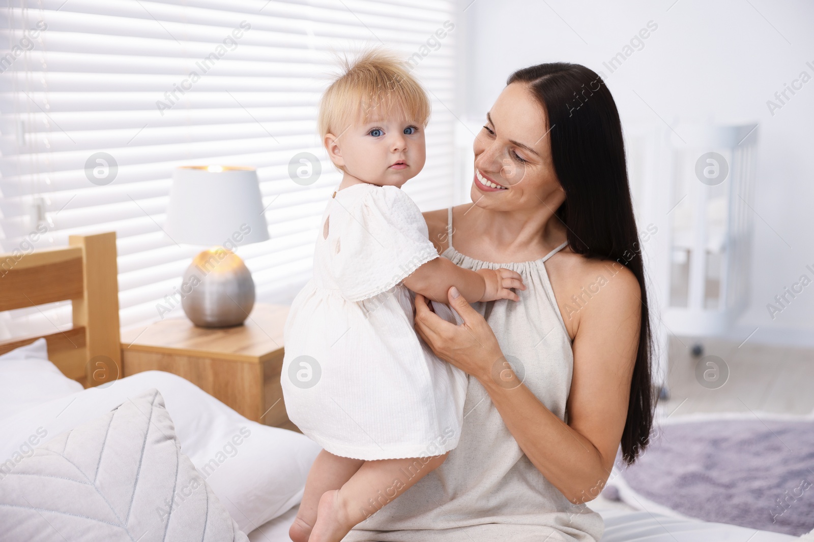 Mother and her cute little baby on bed in room Photo of Mother and her cute little baby on bed in room