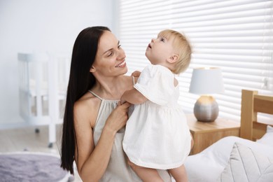 Photo of Mother and her cute little baby on bed in room