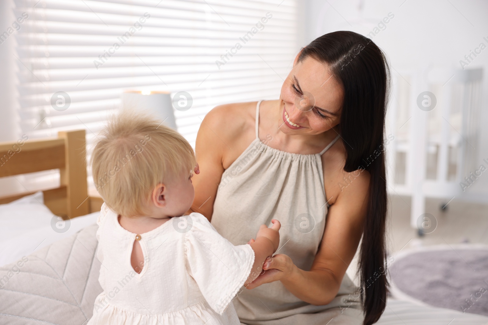 Mother and her cute little baby on bed in room Photo of Mother and her cute little baby on bed in room