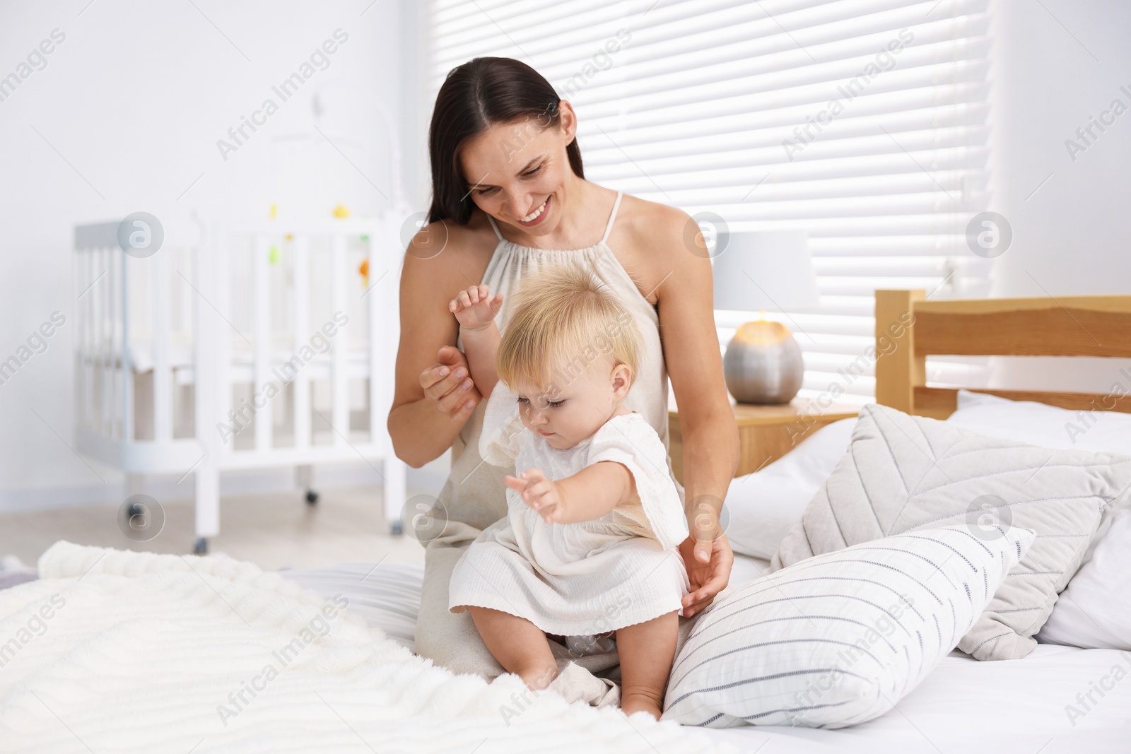 Photo of Mother and her cute little baby on bed in room