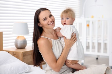 Photo of Mother and her cute little baby on bed in room