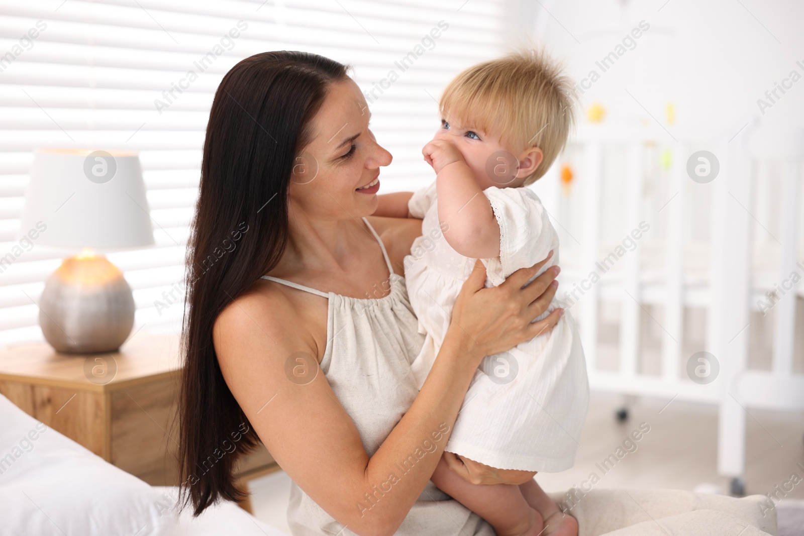Photo of Mother and her cute little baby on bed in room