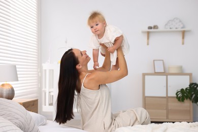 Photo of Mother and her cute little baby on bed in room