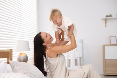 Photo of Mother and her cute little baby on bed in room