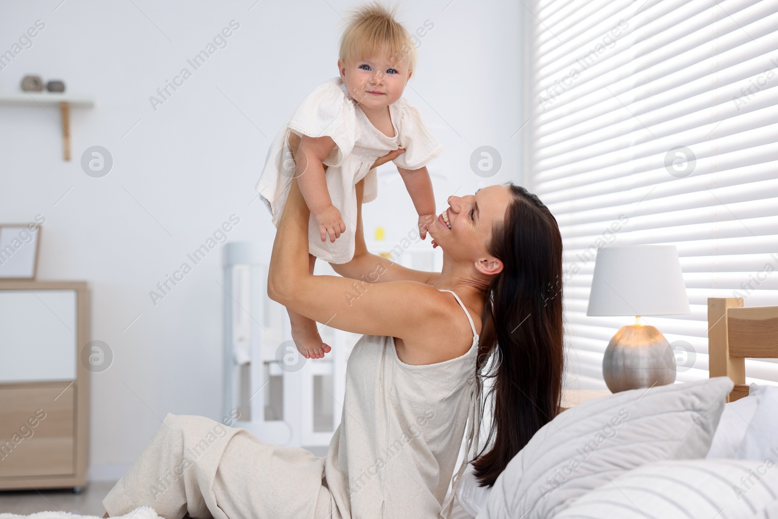 Mother and her cute little baby on bed in room Photo of Mother and her cute little baby on bed in room