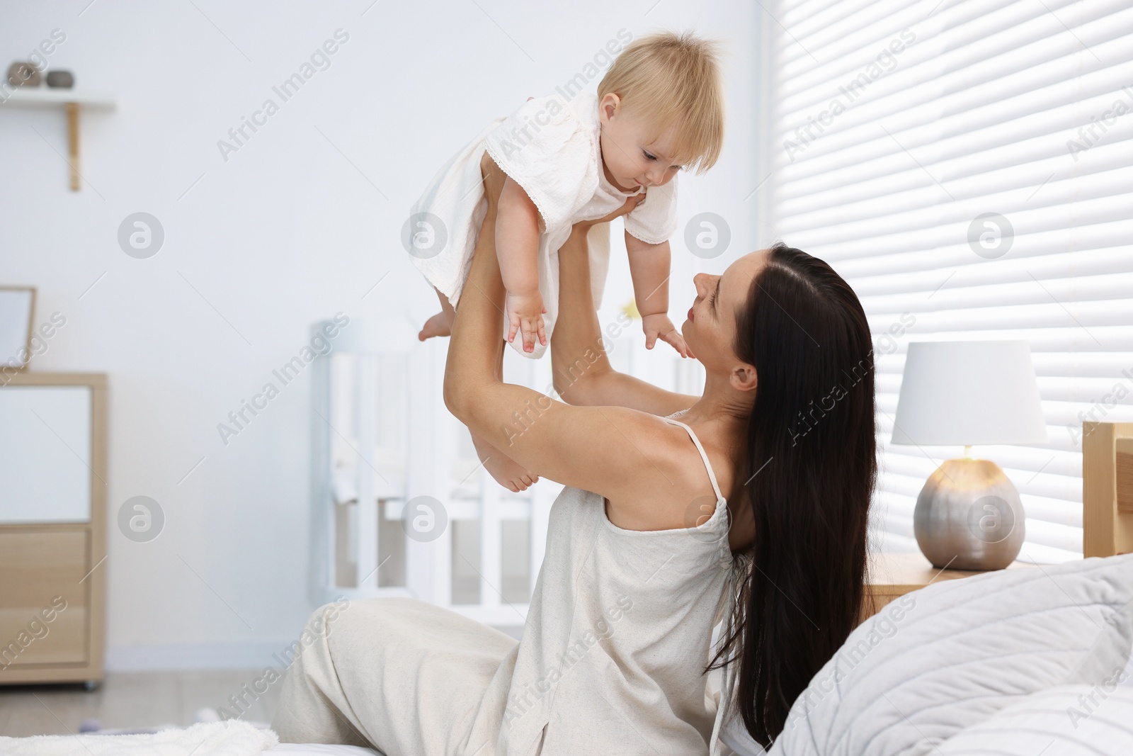 Mother and her cute little baby on bed in room Photo of Mother and her cute little baby on bed in room