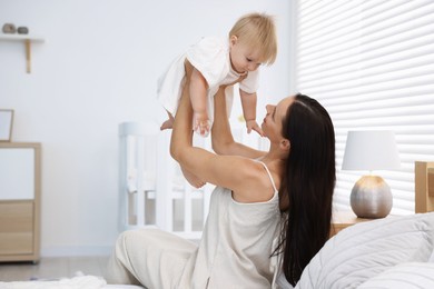 Photo of Mother and her cute little baby on bed in room