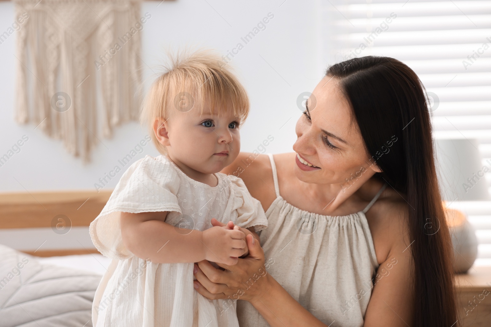 Mother and her cute little baby on bed in room Photo of Mother and her cute little baby on bed in room