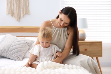 Photo of Mother and her cute little baby on bed in room