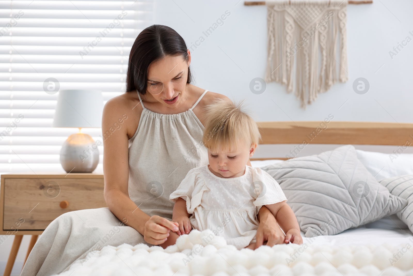 Mother and her cute little baby on bed in room Photo of Mother and her cute little baby on bed in room
