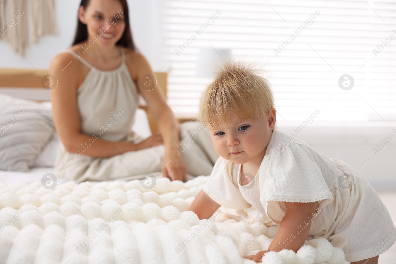 Photo of Mother and her cute little baby on bed in room, selective focus