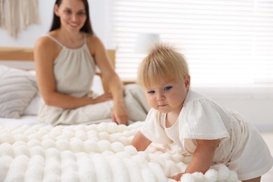 Photo of Mother and her cute little baby on bed in room, selective focus