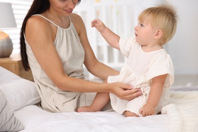 Photo of Mother and her cute little baby on bed in room, closeup