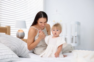 Photo of Mother and her cute little baby on bed in room