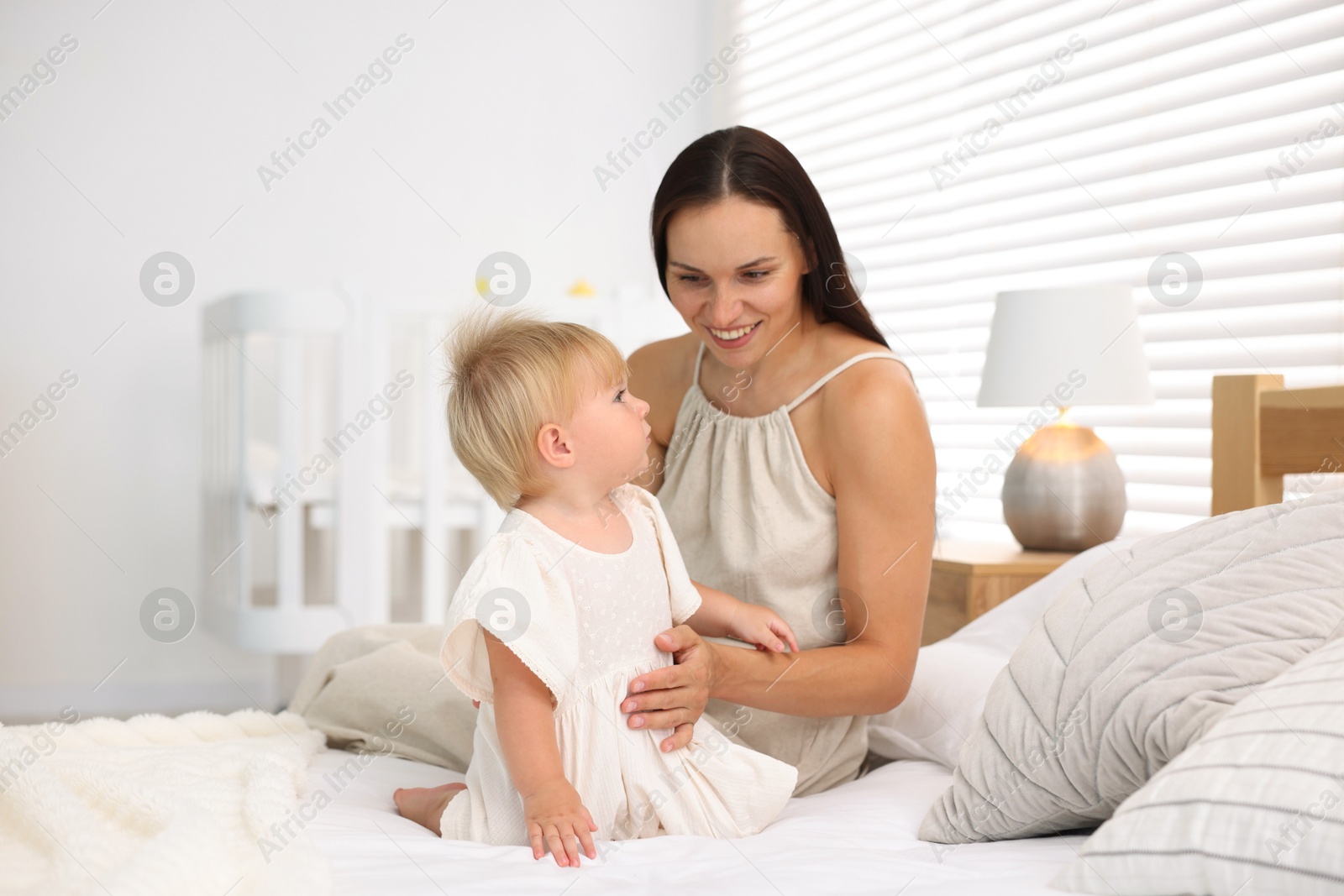 Mother and her cute little baby on bed in room Photo of Mother and her cute little baby on bed in room